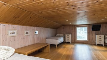 A cabin with a wooden interior, a bed, a bench, a small table, and a window with blinds.