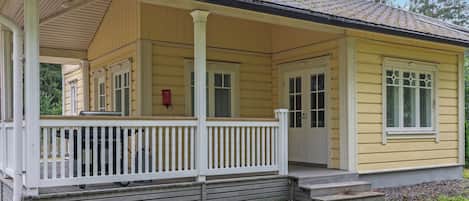 A yellow single-story house with a porch, a chimney, and a red fire hydrant.
