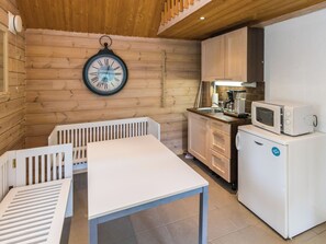 A compact kitchen with wooden walls, a white table, and a clock. - Koivuranta by Interhome (Pori)