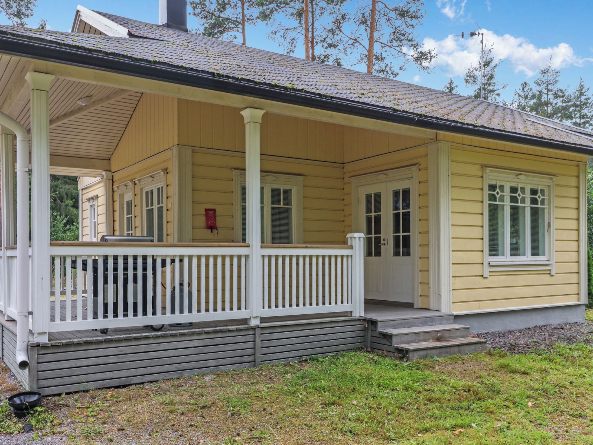 A single-story yellow house with a porch, a chimney, and a small front yard.