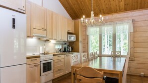 Une cuisine compacte avec des meubles en bois, un réfrigérateur blanc, une cuisinière et une table à manger avec des chaises.