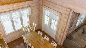 Un intérieur en bois comprenant une table à manger, des chaises, un lustre et un canapé.