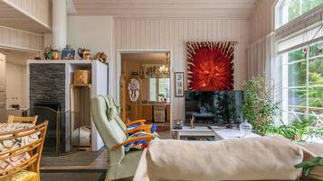 Una sala de estar acogedora con chimenea, un televisor grande y una llamativa decoración roja en la pared.