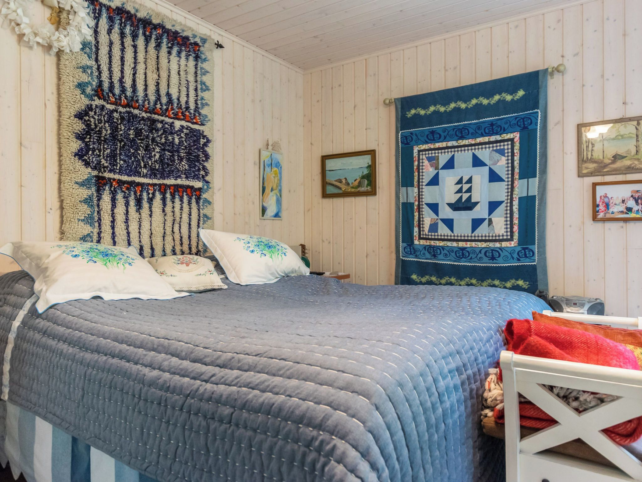 Un dormitorio con una cama grande, cabecera de madera, colcha acolchada y un tapiz en la pared.