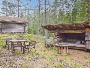 A rustic cabin with a wooden table and chairs, surrounded by a forest. - Metsätupa by Interhome (Raasepori)