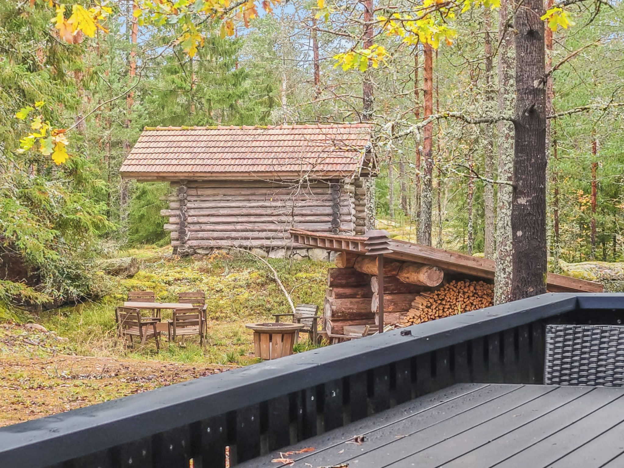 A rustic log cabin with a sloped roof, surrounded by a forest.
