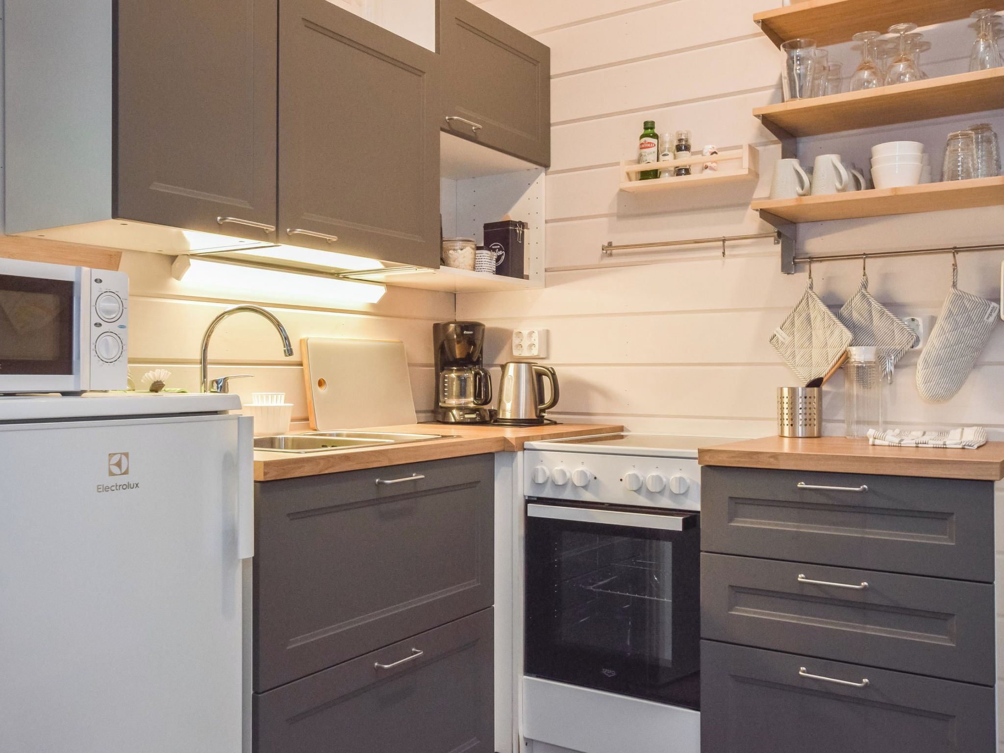 Een functionele keuken met een magnetron, koffiezetapparaat en oven.