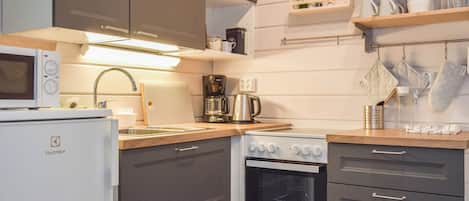 Een functionele keuken met een magnetron, koffiezetapparaat en oven.