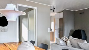 A modern living room with a wooden dining table, a white vase, and a grey sofa with patterned cushions. - Villa havet by Interhome (Porvoo)