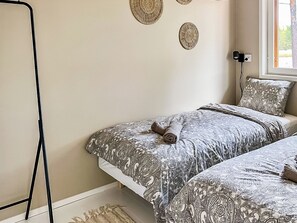 A bedroom with two beds, patterned bedding, a window with a view, and decorative wall art. - Villa havet by Interhome (Porvoo)