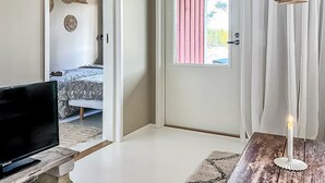 A bedroom with a bed, a television on a stand, a door with a window, and a table with a candle. - Villa havet by Interhome (Porvoo)