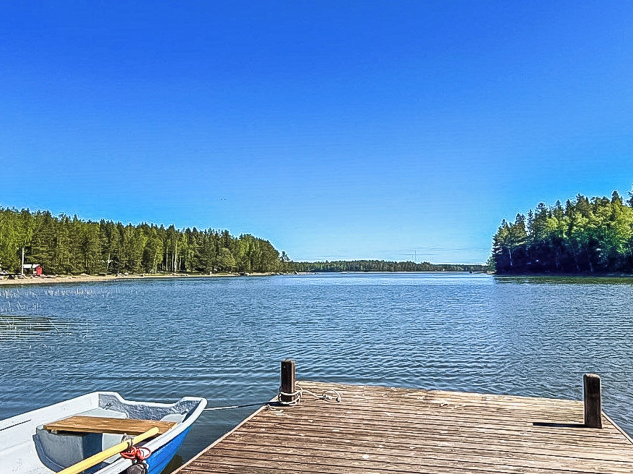 A wooden dock extending into a calm lake with a clear sky above.