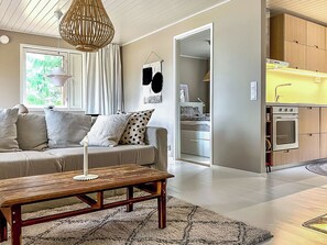 A modern living room with a sofa, a coffee table, and a kitchen area with cabinets and a stove. - Villa havet by Interhome (Porvoo)