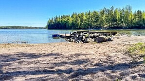 A sandy beach with a dock and a small boat. - Villa havet by Interhome (Porvoo)