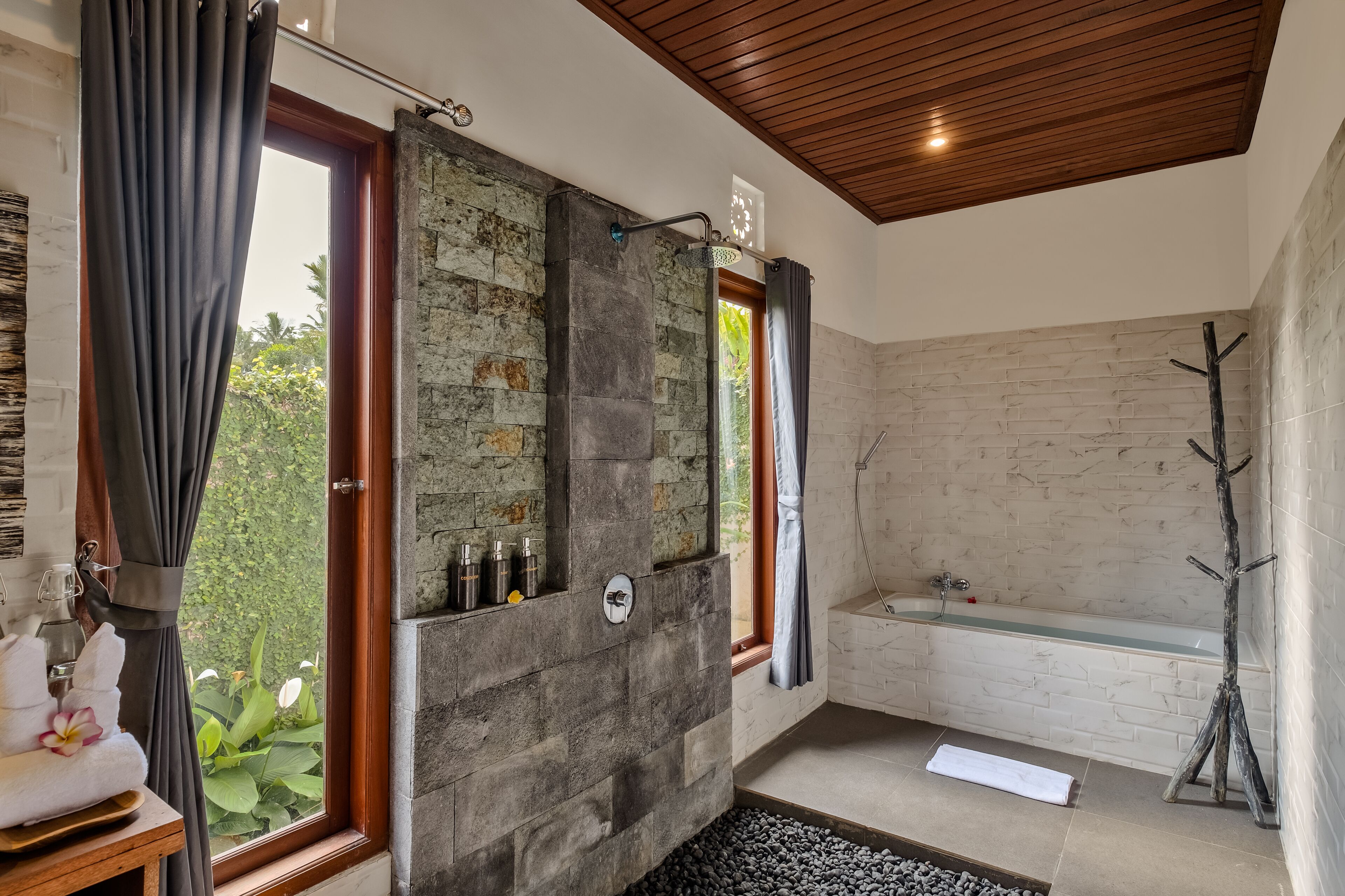 A bathroom with a stone wall, a bathtub, and a shower area.