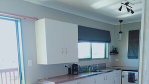 Una cuina moderna amb armaris blancs, taulell de fusta i zona menjador amb taula i cadires de fusta.