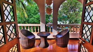 An outdoor seating area with wicker furniture and a view of lush greenery. - Luxury Vintage Villa in the heart of North Goa. (Verla Canca)