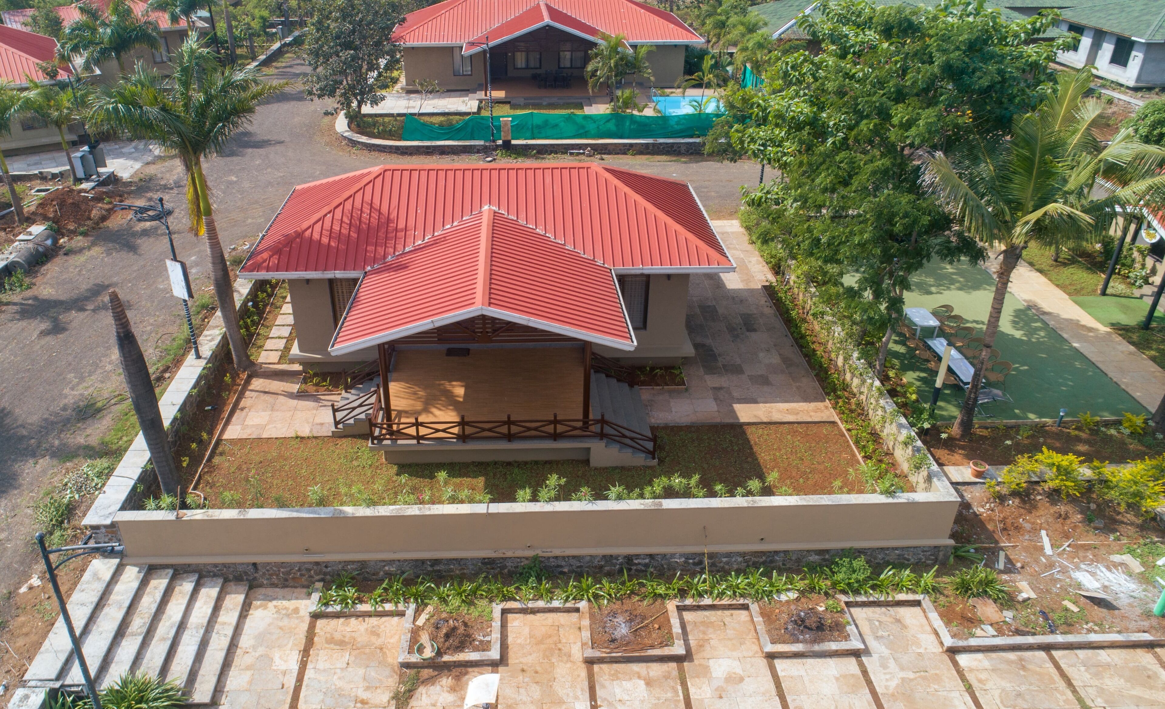 Un bâtiment moderne avec un toit rouge, un espace extérieur abrité et un jardin aménagé.