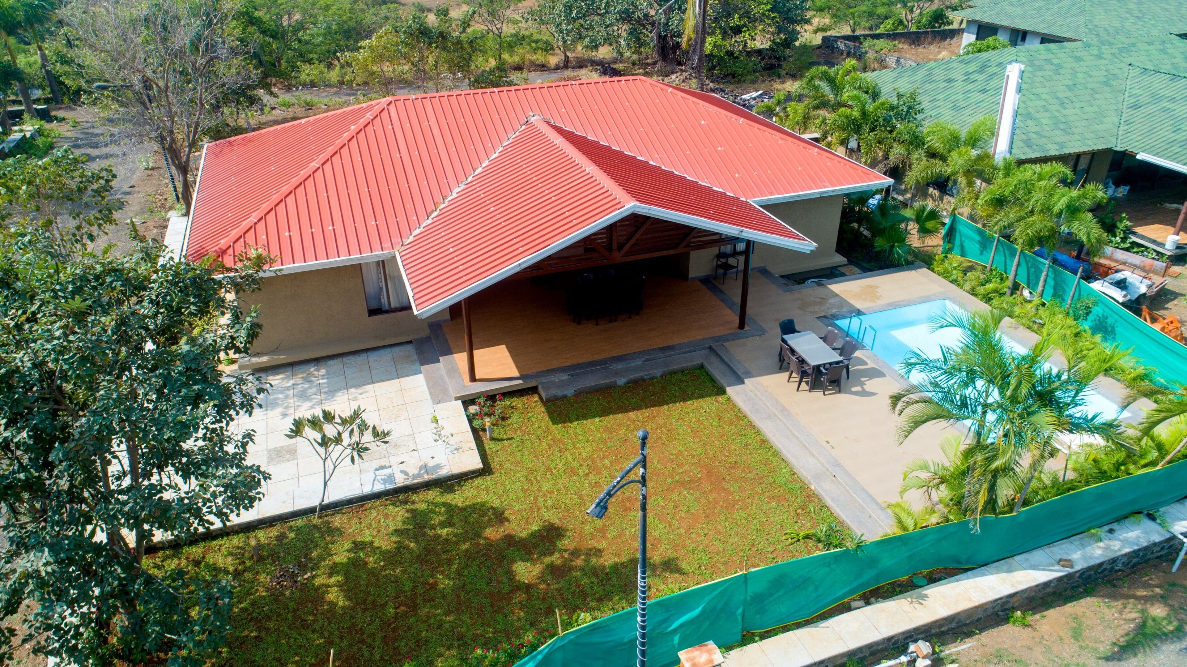 A house with a red roof, a covered patio, and a swimming pool.