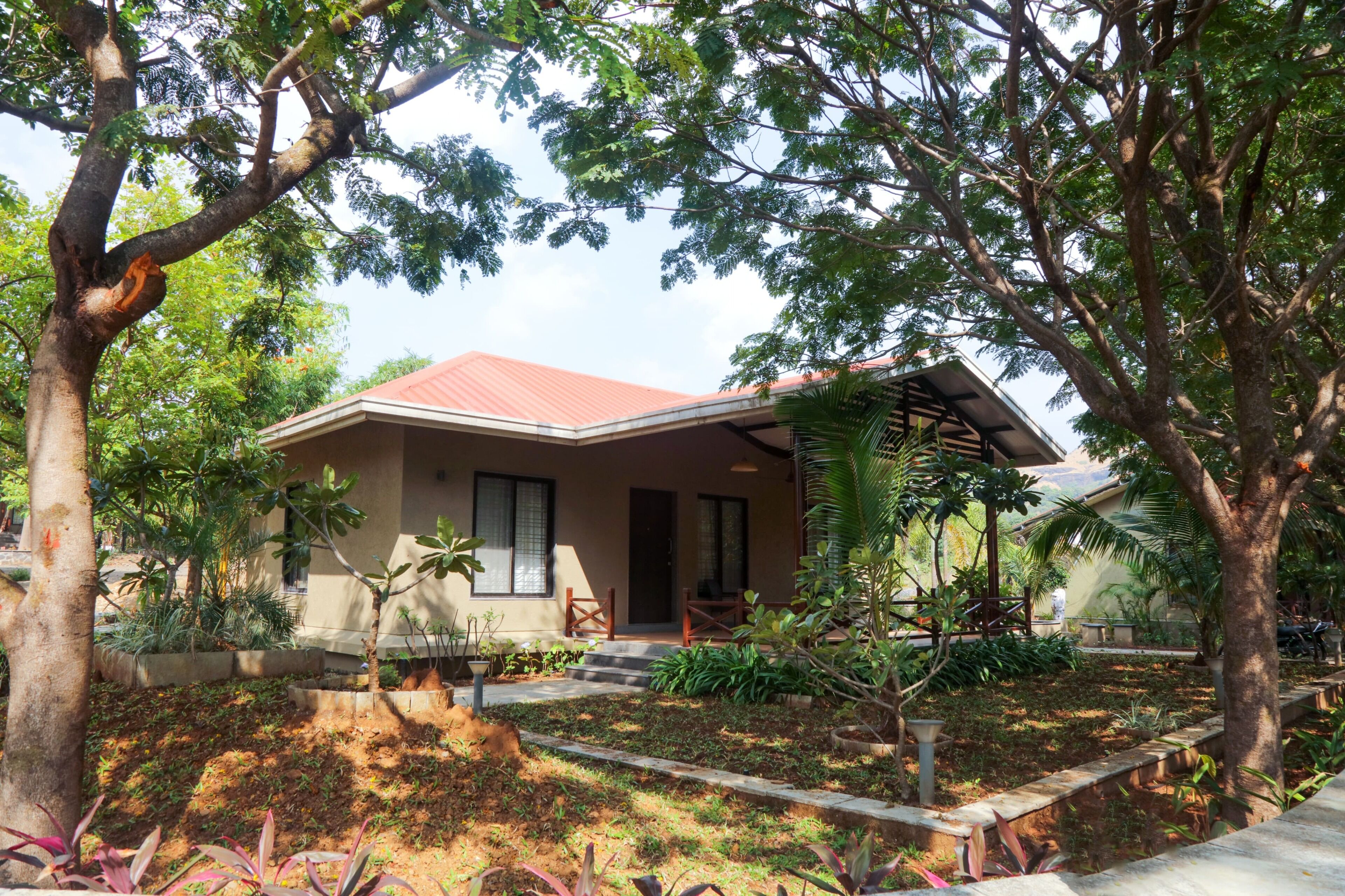 A house with a red roof, surrounded by trees and plants.