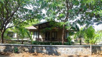 A house with a stone wall, a wooden deck, and surrounding greenery.