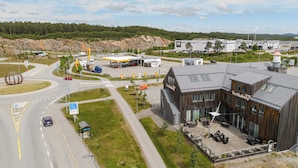 A modern building with a wooden facade and a rooftop terrace with outdoor seating. - Vertikalen (Lillesand)