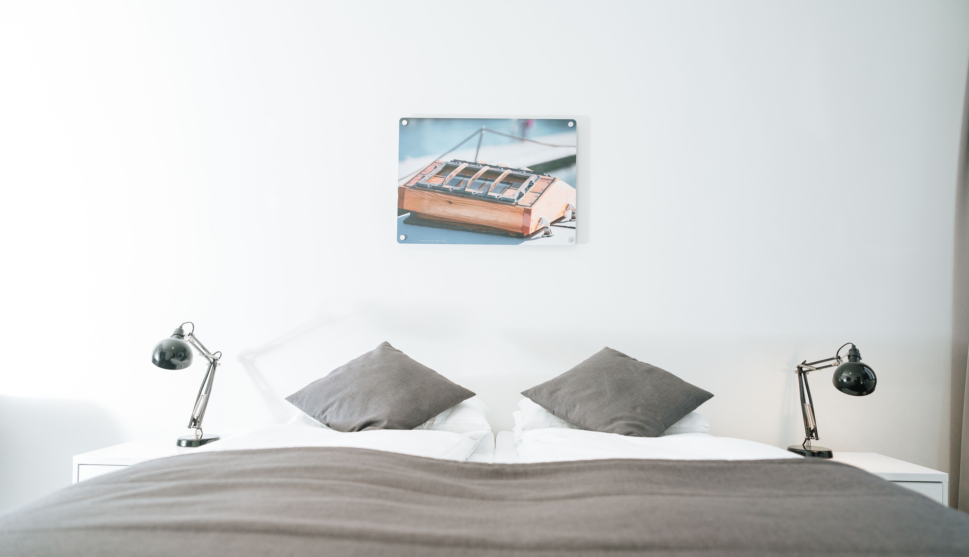 Un dormitorio con una cama, dos lámparas de noche y un cuadro en la pared.