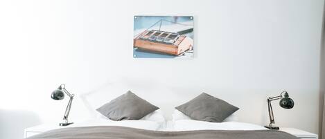A bedroom with a bed, two bedside lamps, and a framed picture on the wall.