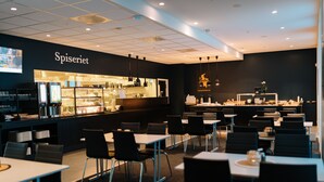 A modern cafe interior with a bar area, seating arrangements, and a visible menu board. - Vertikalen (Lillesand)