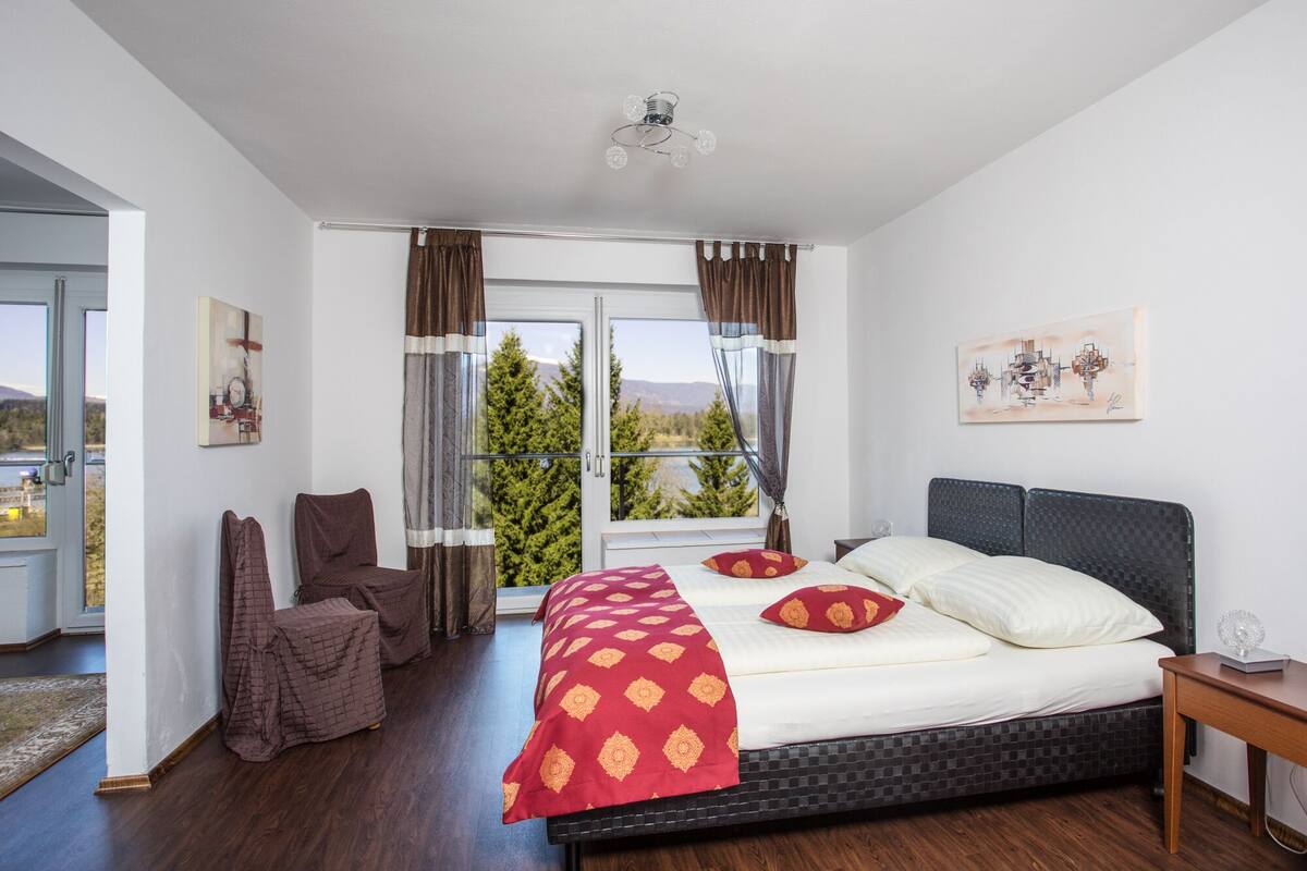 Una camera da letto con un letto grande, una sedia, un comodino e una finestra con tende.