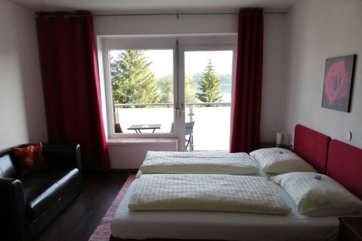 Una camera d'albergo con due letti, un divano e un balcone con tavolo e sedie.