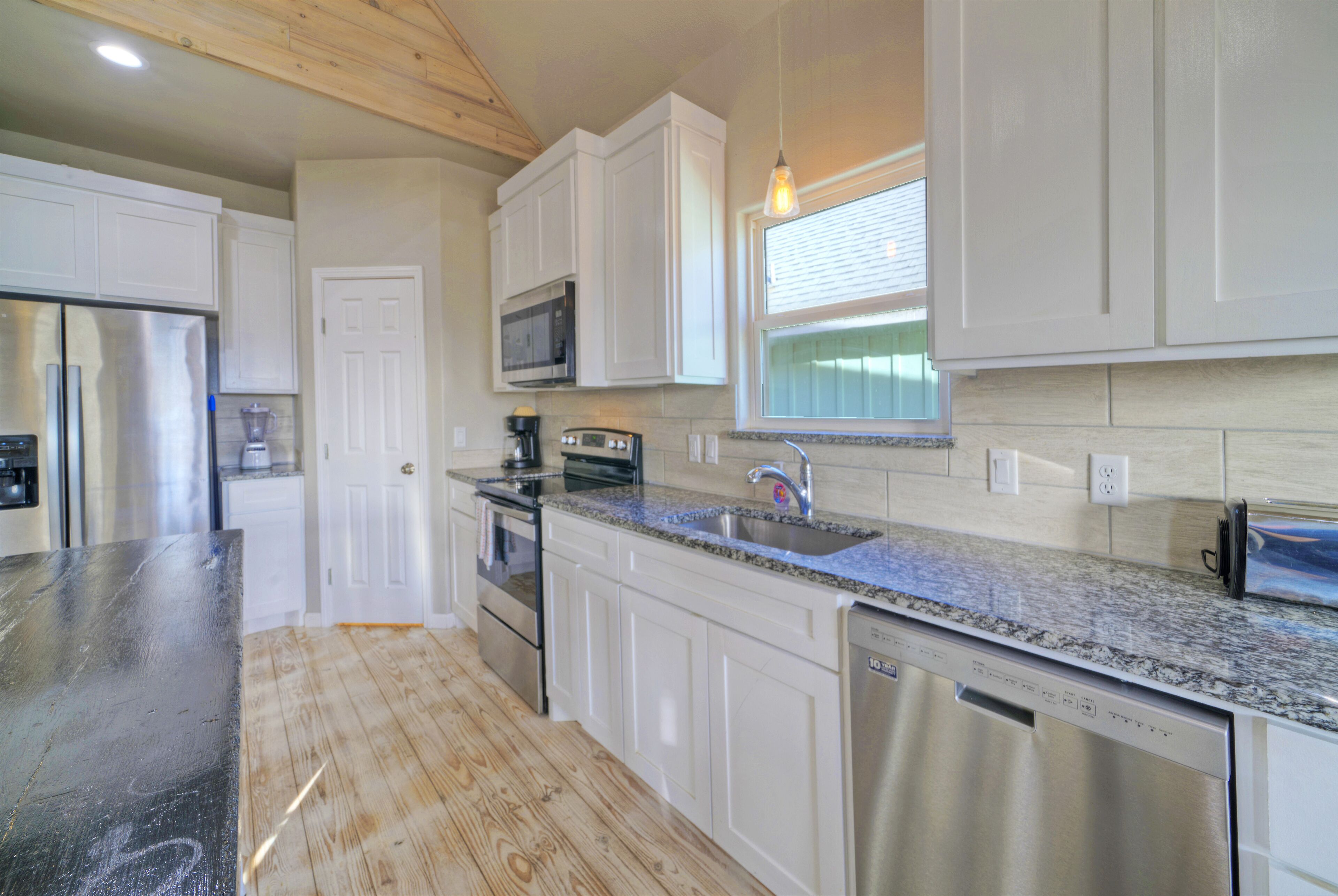 A modern kitchen with white cabinets, stainless steel appliances, and a granite countertop.