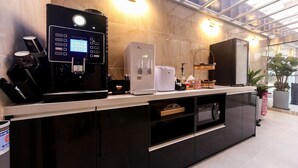 A modern kitchen with a coffee machine, a refrigerator, and a microwave. - ONNA HOTEL (Busan)