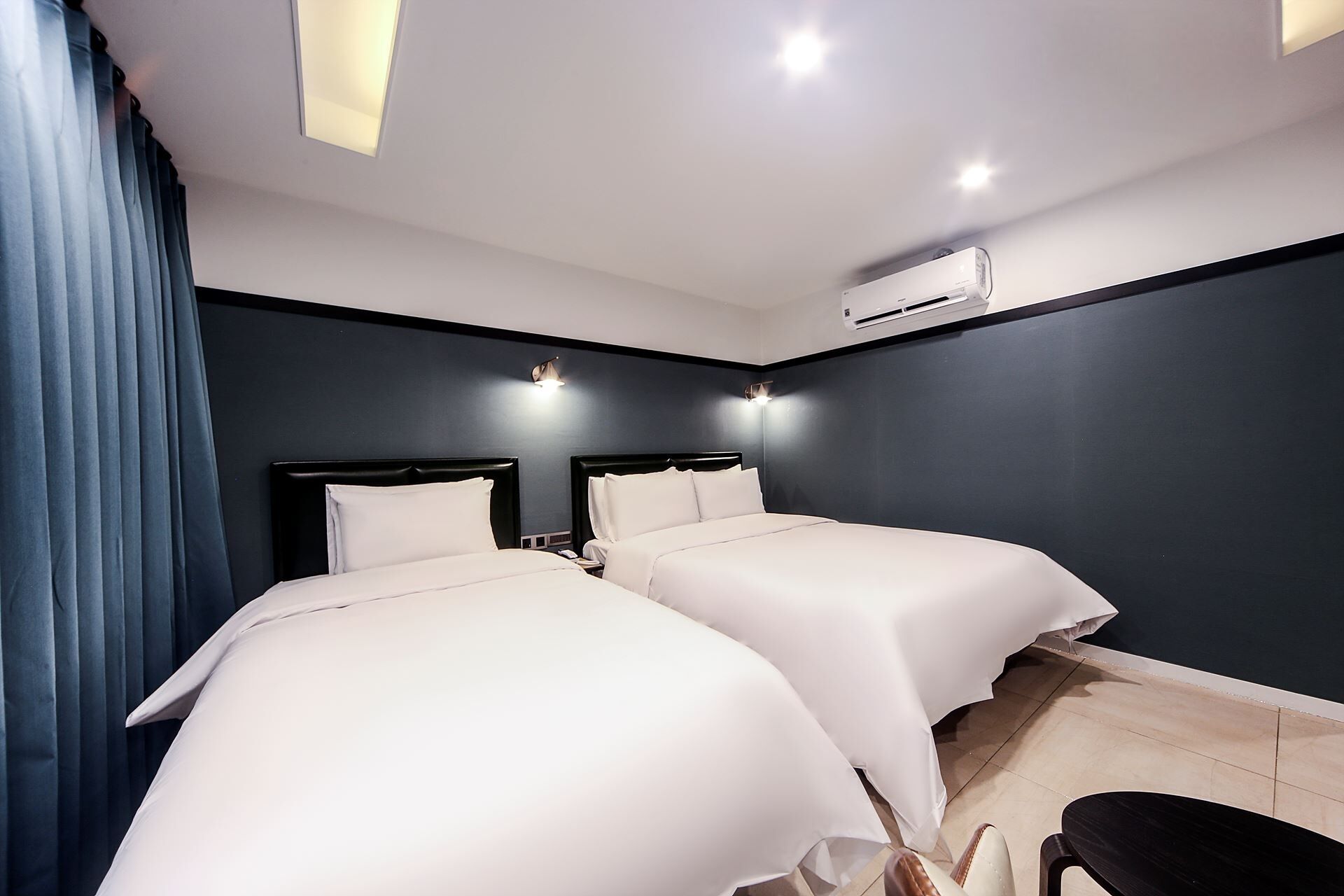 Ein modernes Hotelzimmer mit zwei Betten, einem Schreibtisch und einer Klimaanlage.