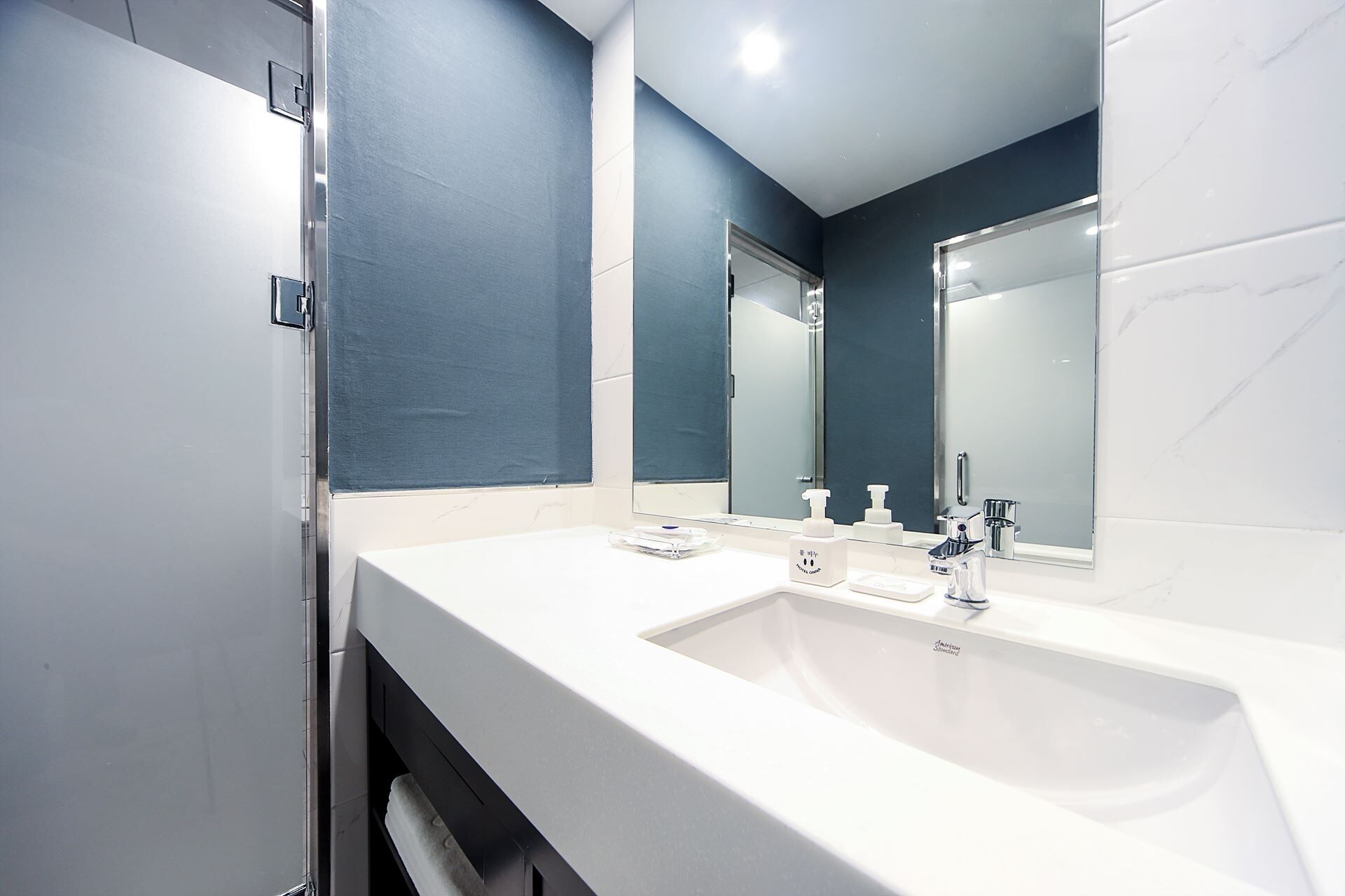 Un baño moderno con un lavamanos blanco, un espejo grande y una pared de acento azul.