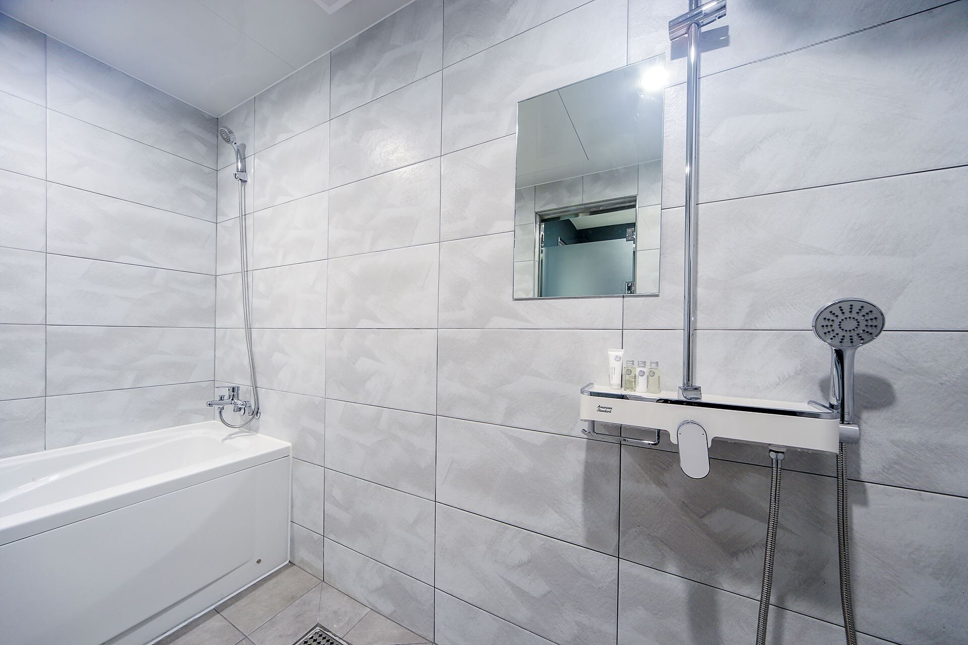 Bañera con ducha, artículos de tocador de diseñador, secador de pelo