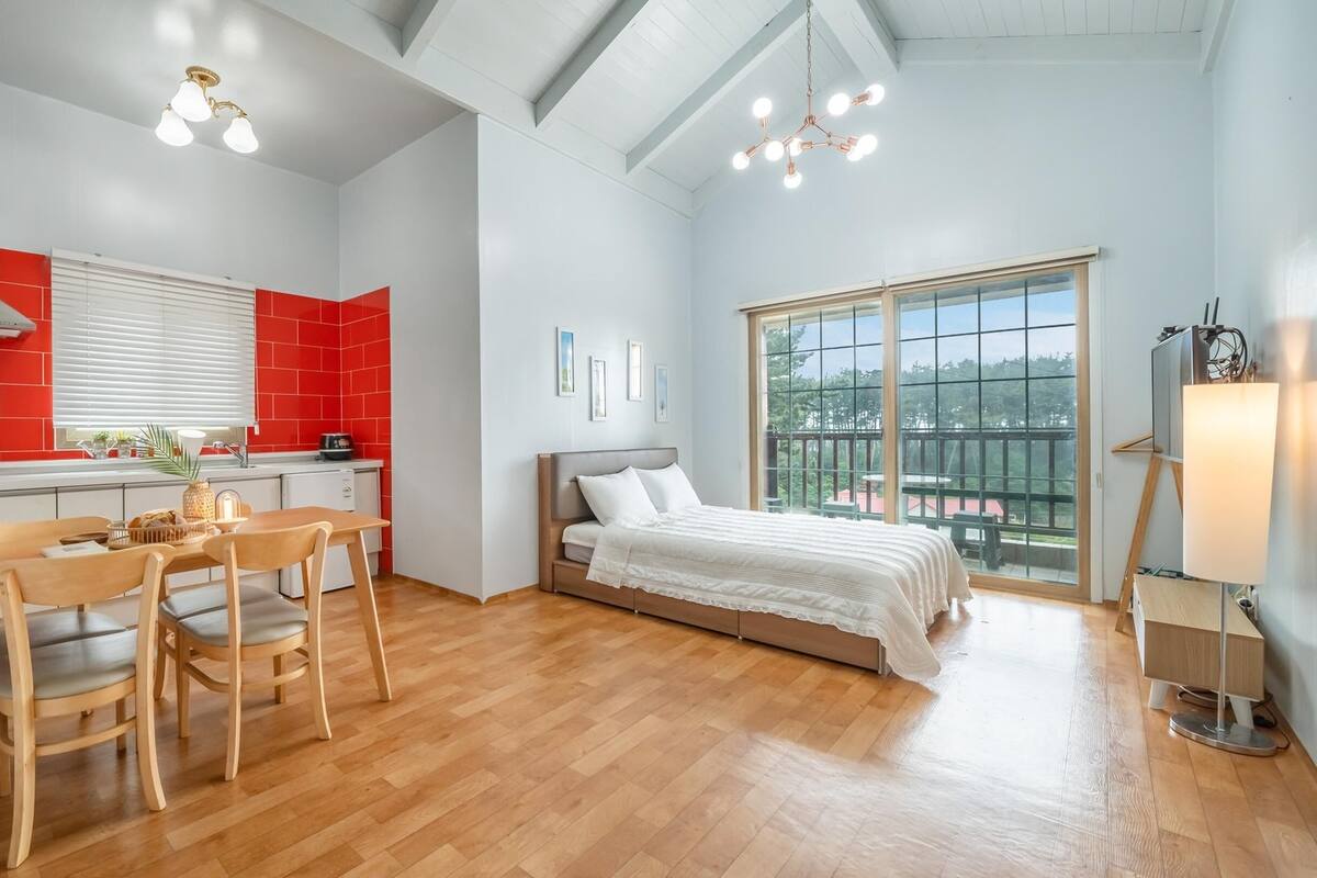 A modern apartment with a kitchen, dining area, and a bedroom with a balcony.