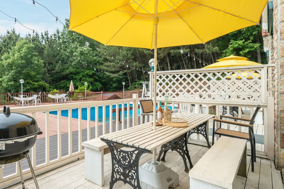 A wooden deck with a pool, outdoor furniture, and a grill.