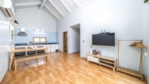 Una cocina moderna con comedor, televisor montado en la pared y piso de madera.