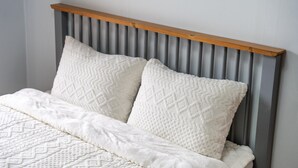 Una cama con cabecera de madera y dos almohadas.