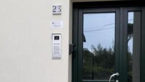 L’entrée d’un immeuble se distingue par une porte vert foncé, une plaque numérotée et un petit espace extérieur aménagé en coin salon.
