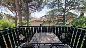Une terrasse extérieure avec une table et des chaises carrelées, entourée d’une rambarde en métal noir.