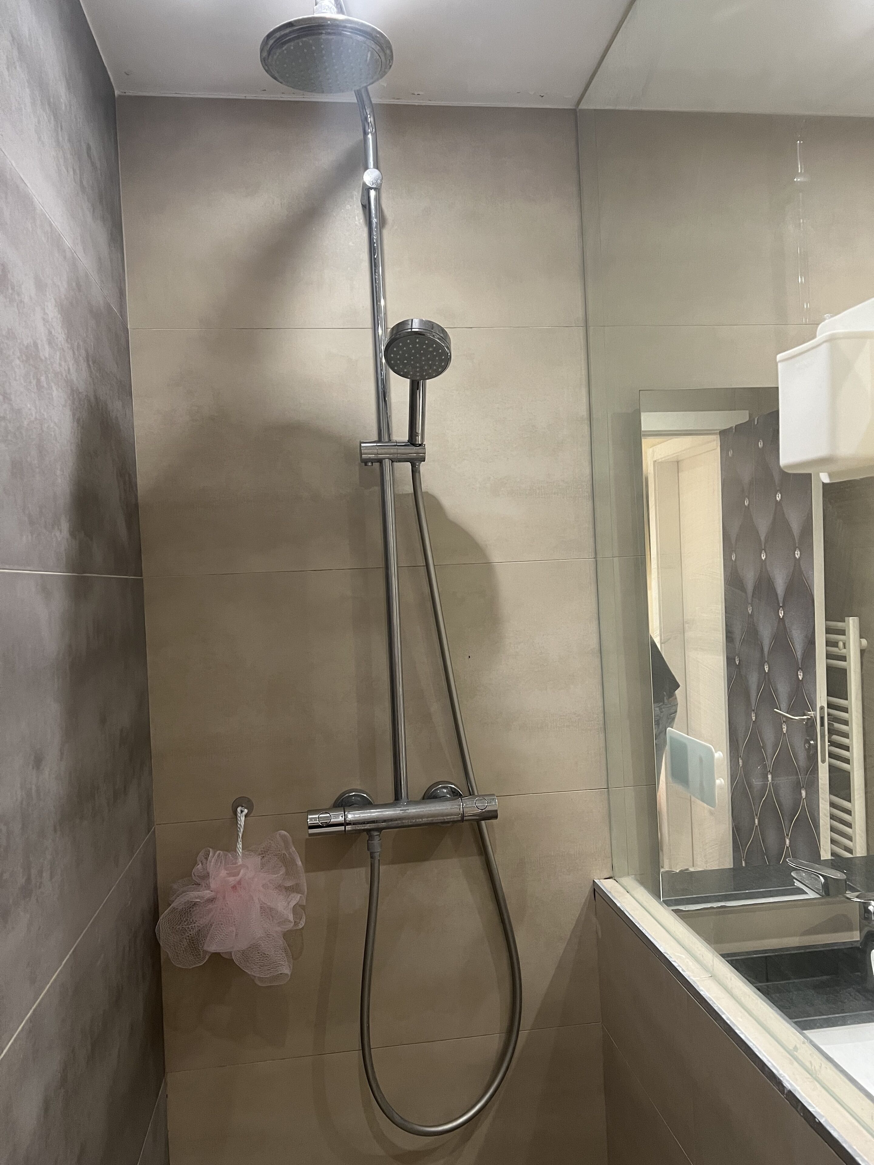 A modern bathroom with a shower, a glass enclosure, and a towel rack.