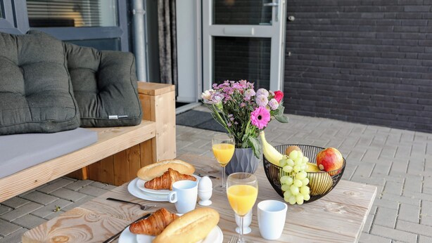A breakfast setup with croissants, eggs, juice, and a fruit bowl on a wooden table. - Appartement 16 Wemeldinge (Wemeldinge)