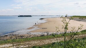 A beach with a sandy shore, a calm sea, and a distant ferry. - Appartement 16 Wemeldinge (Wemeldinge)