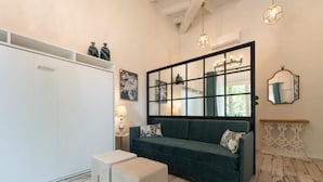 Ein modernes Wohnzimmer mit einem dunkelgrünen Sofa, einem weißen Kleiderschrank und einem großen Spiegel.