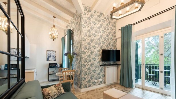 Ein Wohnzimmer mit einer Couch, einem Fernseher, einem Kamin und einem Balkon mit Sitzgelegenheit.