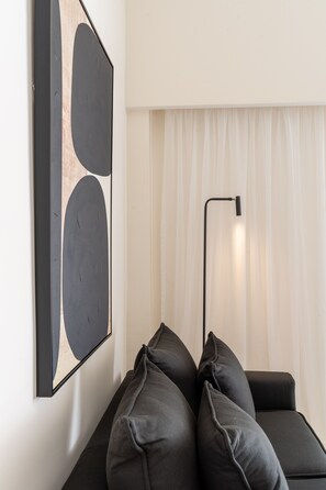 Relax in this stylish living space with a black sofa, floor lamp, and abstract art.
