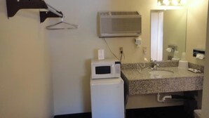 Een kleine badkamer met een magnetron, wastafel en spiegel.