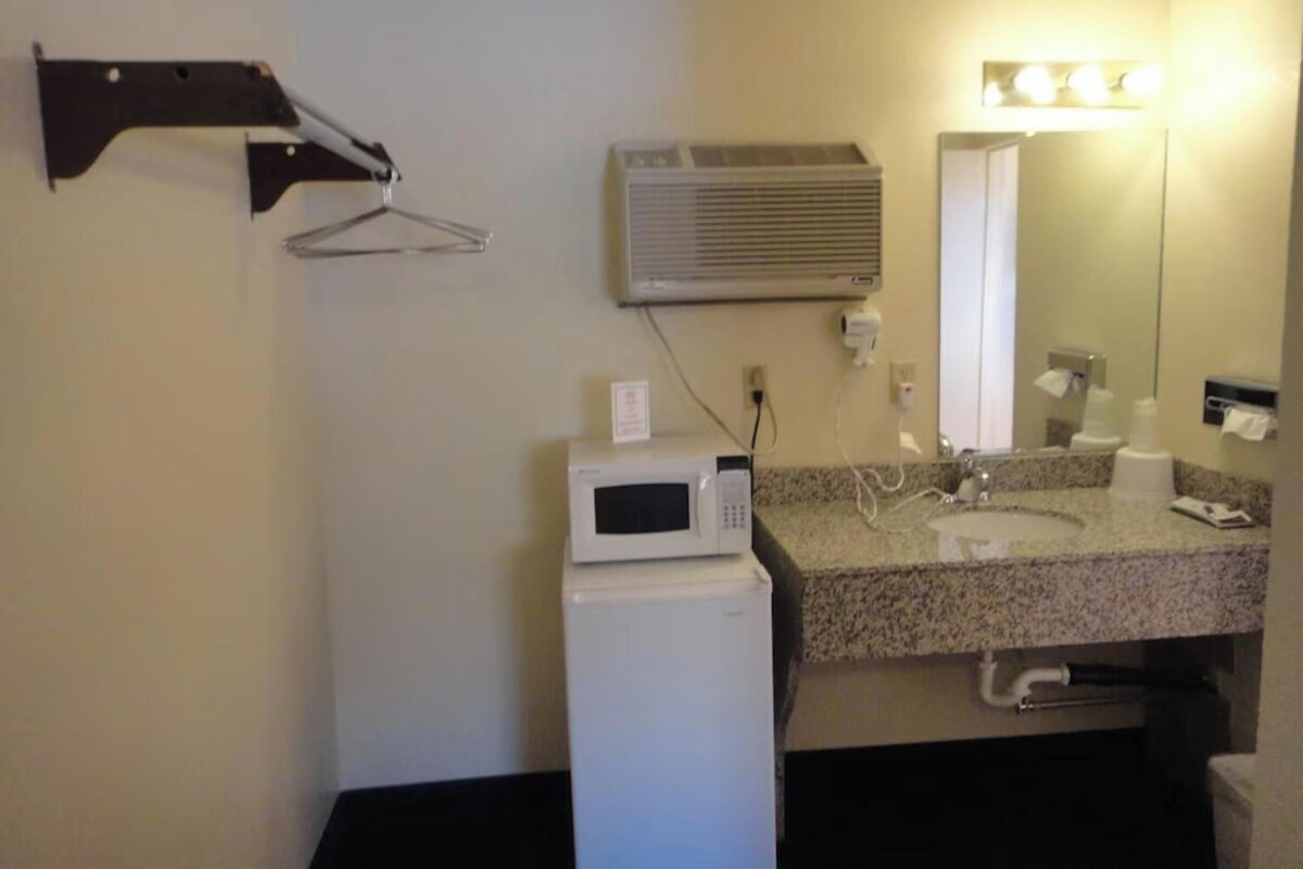 Ein kleines Badezimmer mit Mikrowelle, Waschbecken und Spiegel.